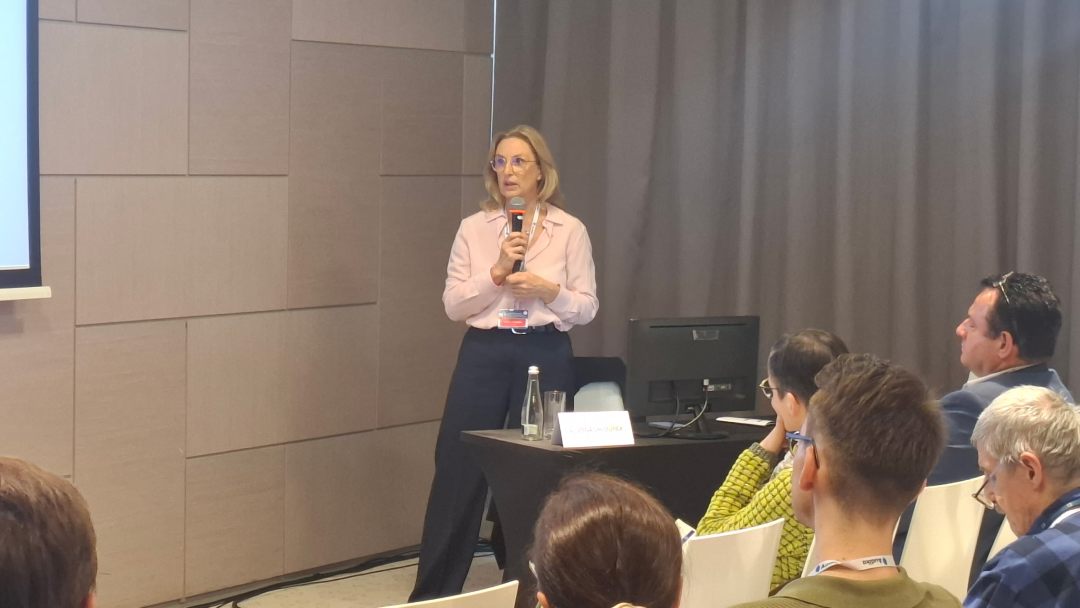 Prelegentka na scenie z mikrofonem w ręku.