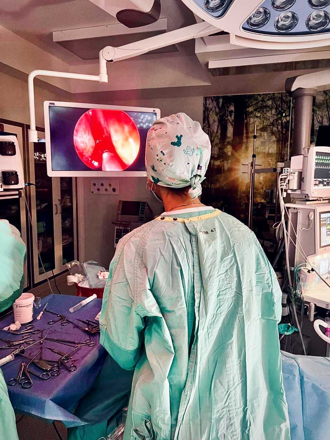 Sala operacyjna, lekarze podczas operacji patrzą w monitor z obrazem zabiegu.