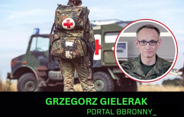Żołnierz na poligonie idący do karetki wojskowej. W kółku Grzegorz Gielerak.