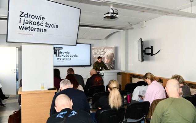 Ujęcie z tyłu sali na słuchaczy wykładu i prowadzącą wykład Barbarę Betiuk.