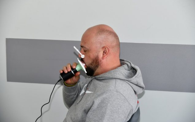 Mężczyzna trzyma w ustach urządzenie do spirometrii.