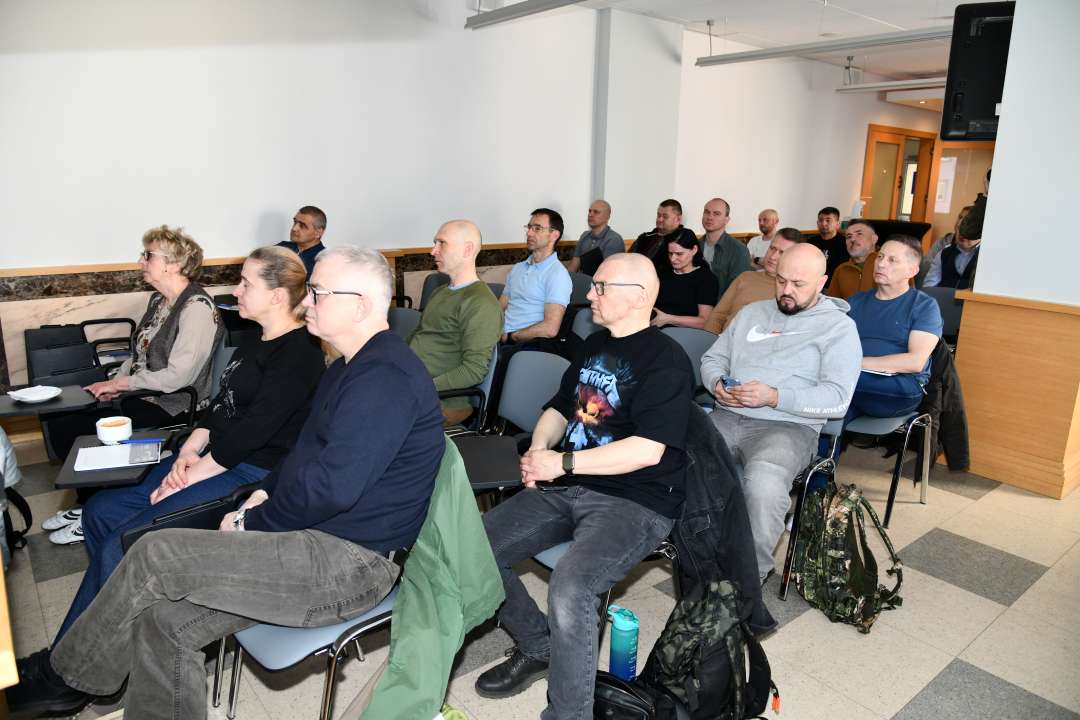 Siedzący słuchacze na sali wykładowej.