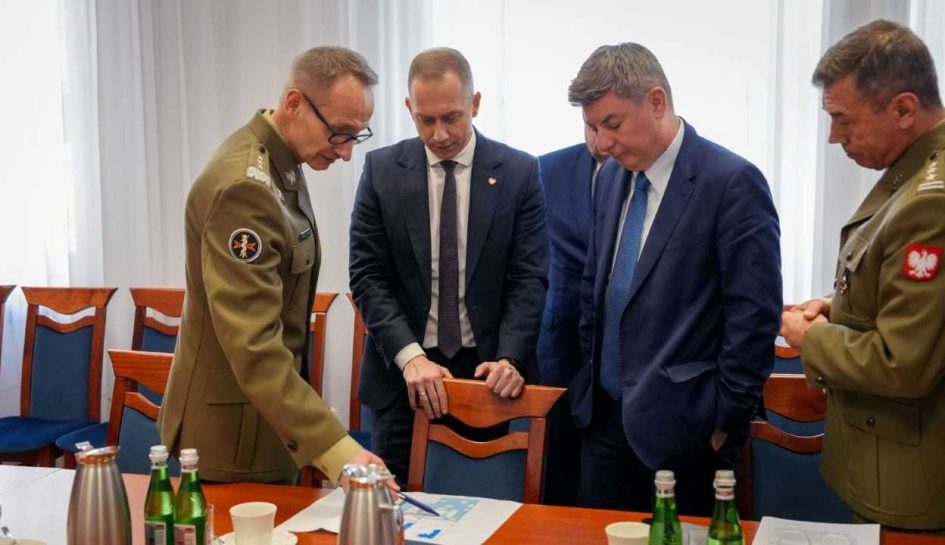 Cezary Tomczyk, Jan Grabiec, Roman Smogorzewsk, Grzegorz Gielerak stoją przy stole i omawiają leżący na nim dokument.