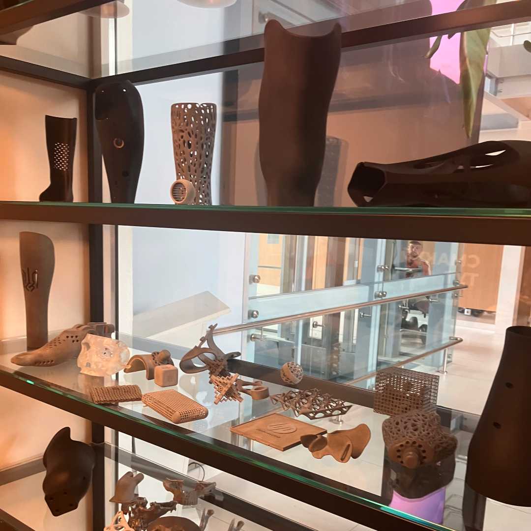 Elementy wydrukowane drukarką 3d protez kończyn i ich elementów w gablocie szklanej.