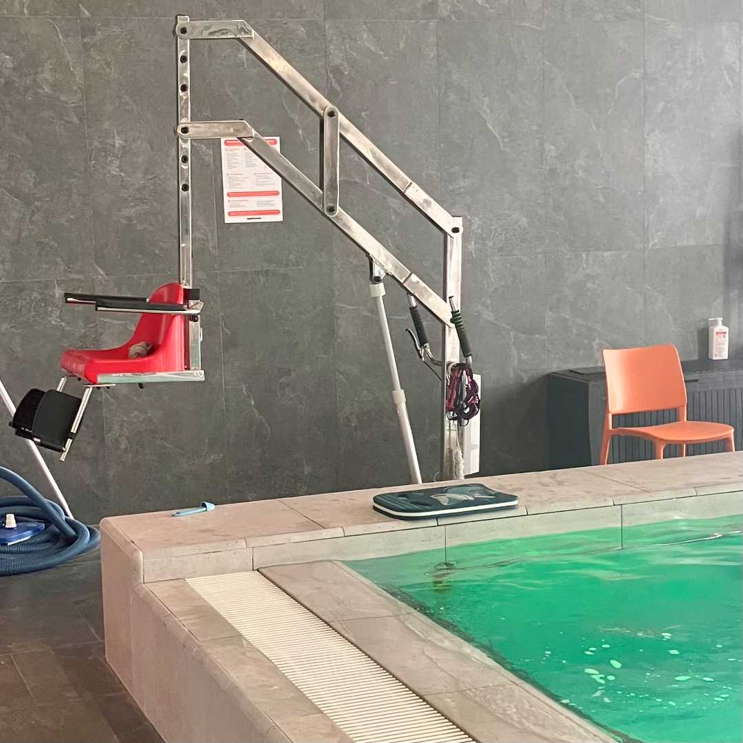 Wysięgnik z krzesełkiem przy basenie rehabilitacyjnym.