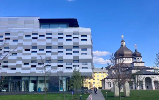 Na pierwszym tle nowoczesny budynek, na drugim planie zabytkowa cerkiew.