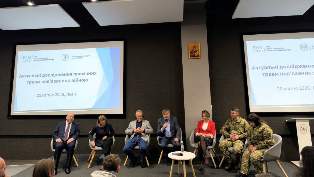 Uczestnicy panelu dyskusyjnego na sali konferencyjnej. Za nimi dwa wyświetlacze z treściami konferencji.