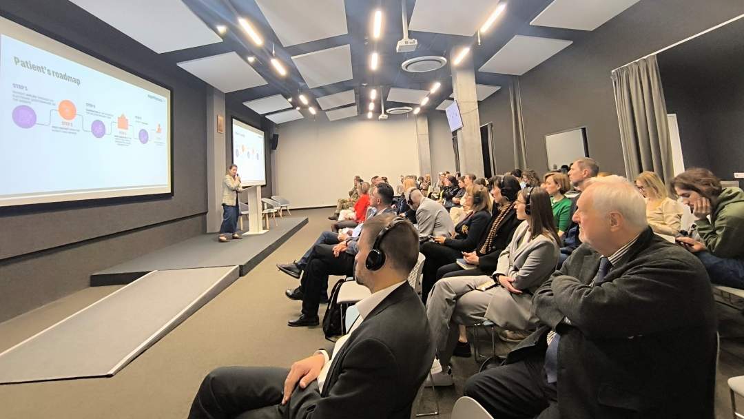 Siedzący słuchacze na sali wykładowej. Przed nimi duży ekran z wyświetloną prezentacją.