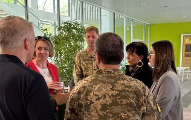 Dyskutujący na korytarzu naukowcy.