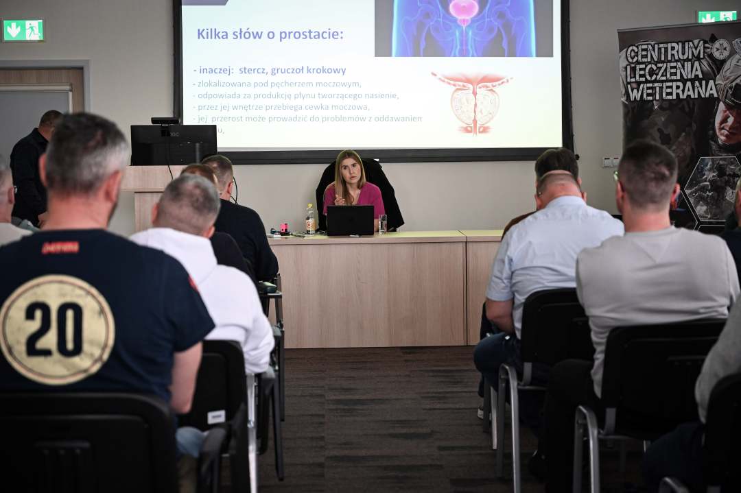 Agnieszka Grabińska prowadzi wykład. Przed nią siedzą słuchacze, za jej plecami na ekranie wyświetlona prezentacja.