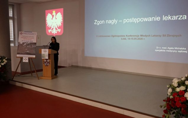 Prelegent przy mównicy za jego plecami wyświetlony slajd prezentacji.