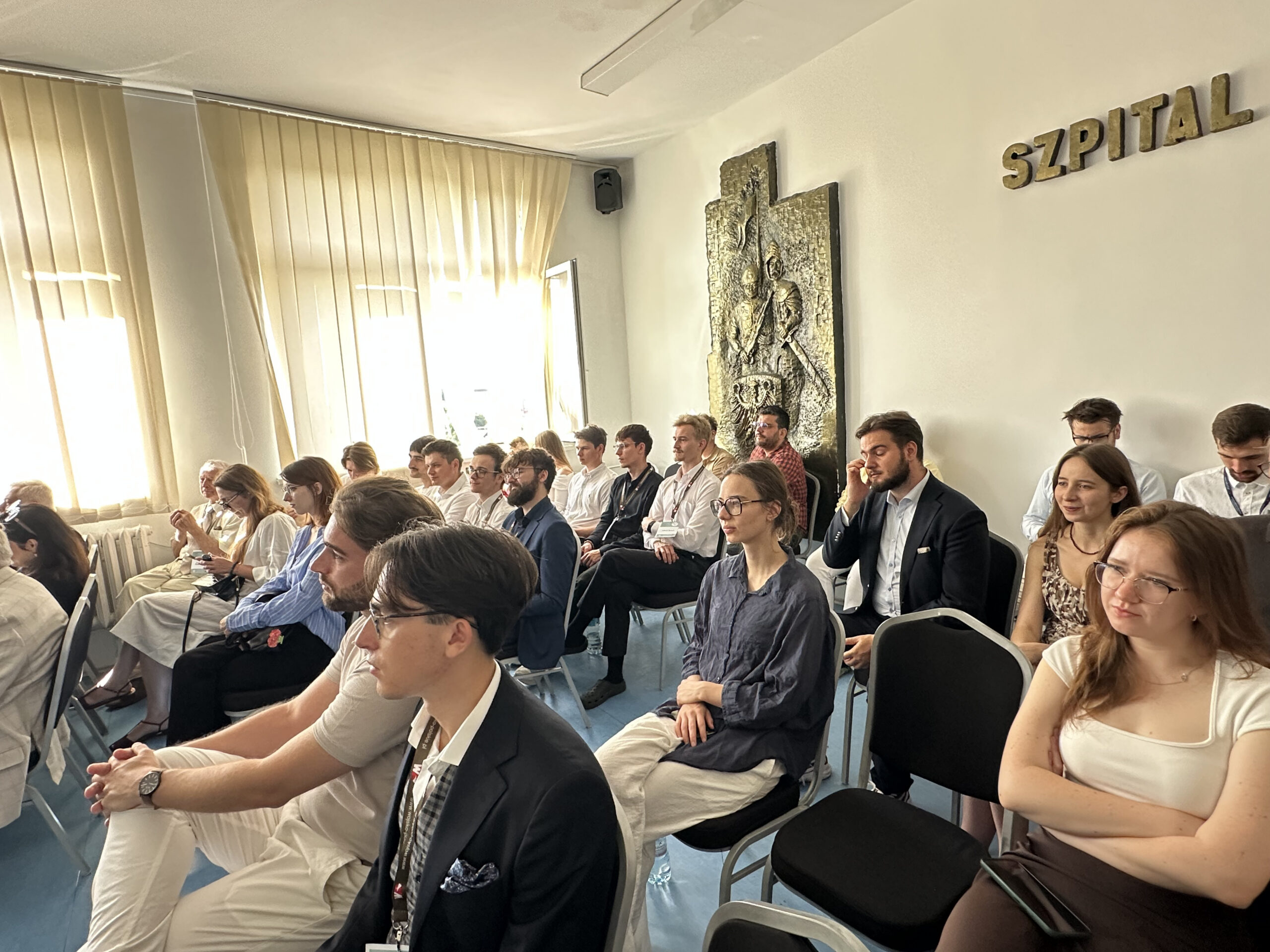 Siedzący słuchacze na sali konferencyjnej