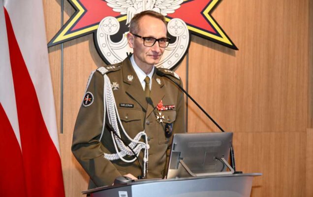 Grzegorz Gielerak przy mównicy. Za jego plecami flaga Polski i logotyp WIM-PIB.