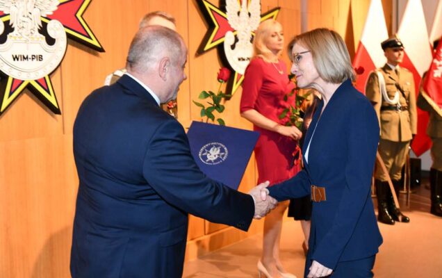 Alojzy Nowak i Grzegorz Gielerak wręczają pracowniczce WIM dyplom.