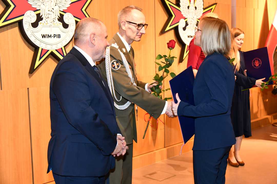 Alojzy Nowak i Grzegorz Gielerak wręczają pracowniczce WIM dyplom.