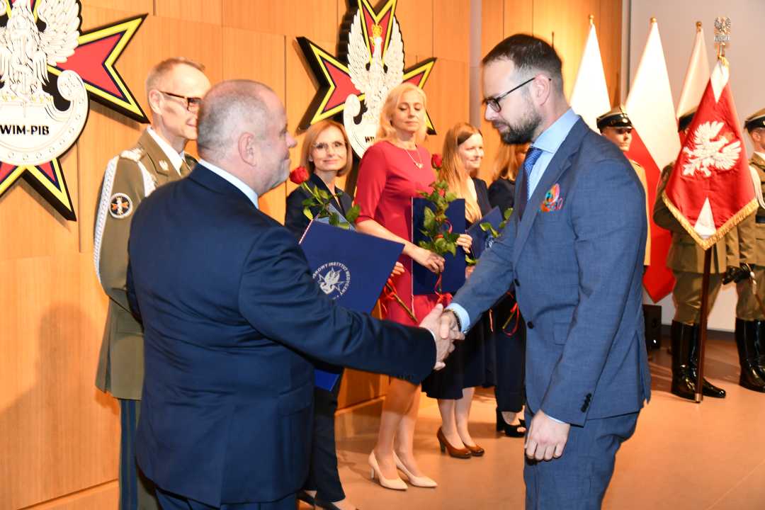 Alojzy Nowak i Grzegorz Gielerak wręczają pracownikowi WIM dyplom.