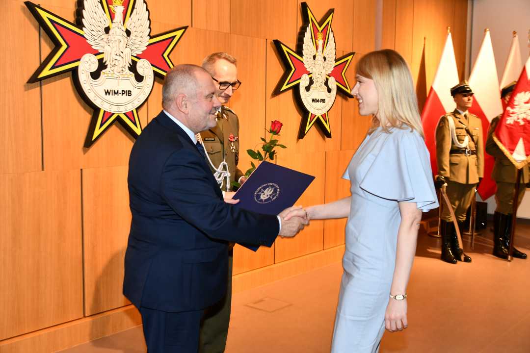 Alojzy Nowak i Grzegorz Gielerak wręczają pracowniczce WIM dyplom.