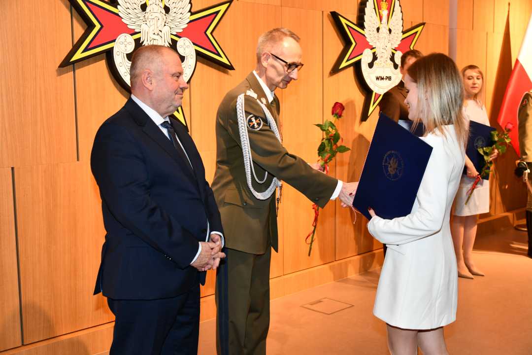 Alojzy Nowak i Grzegorz Gielerak wręczają pracowniczce WIM dyplom.