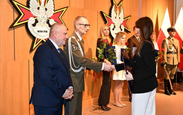 Alojzy Nowak i Grzegorz Gielerak wręczają pracowniczce WIM dyplom.
