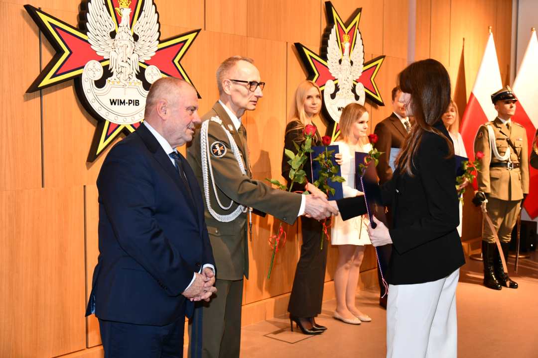 Alojzy Nowak i Grzegorz Gielerak wręczają pracowniczce WIM dyplom.