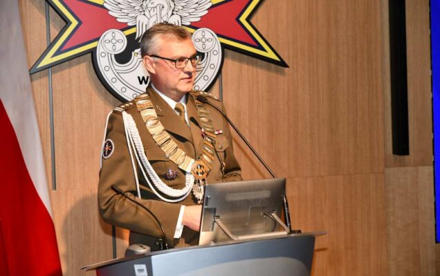 Marek Saracyn przy mównicy. Za nim flaga Polski i logotyp WIM-PIB.