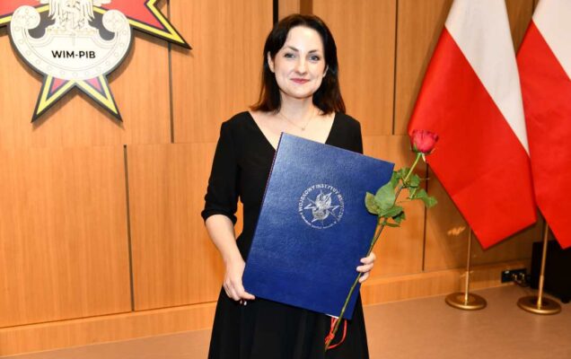 Laureatka z dyplomem i różą w ręce.