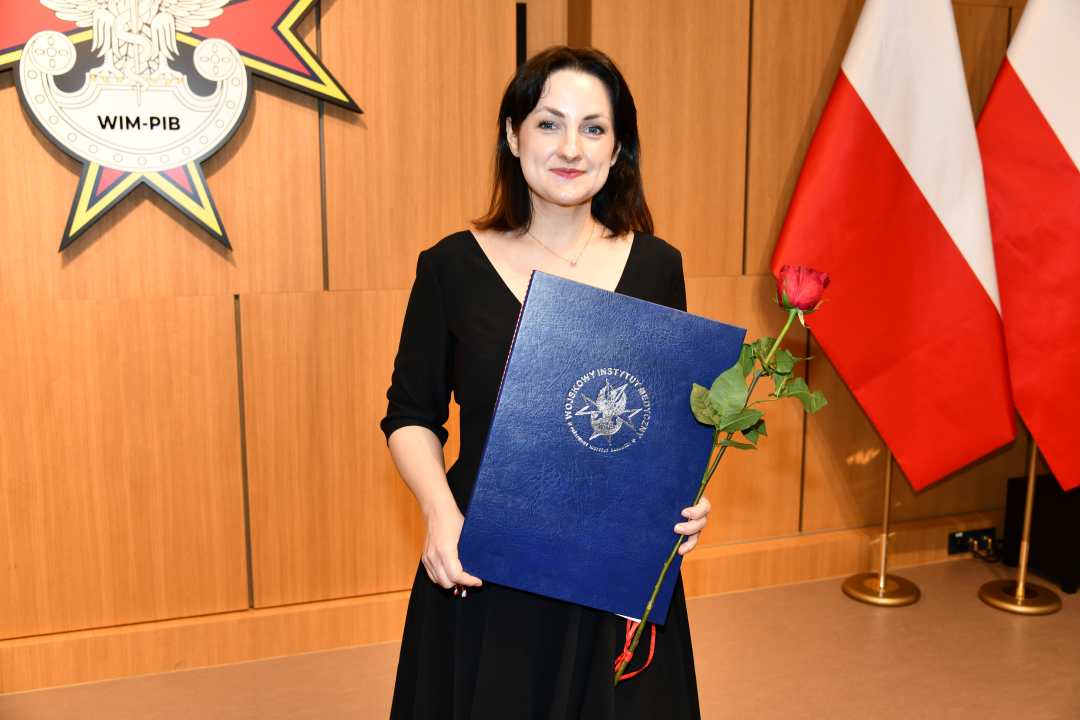 Laureatka z dyplomem i różą w ręce.